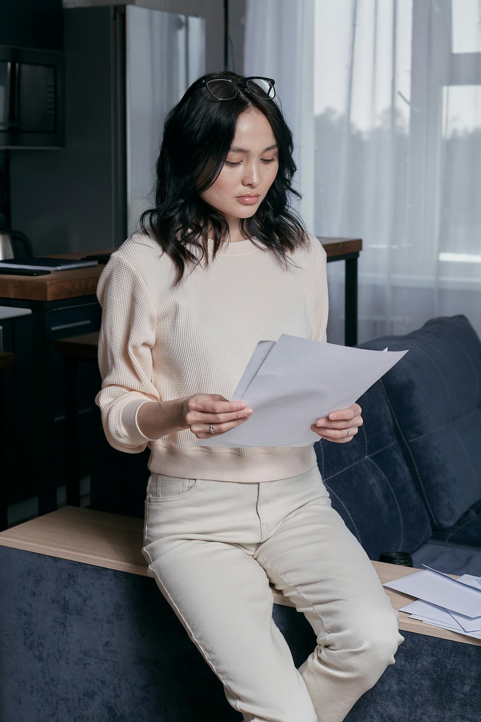 Focused young woman analyzing financial papers in a modern home setting.